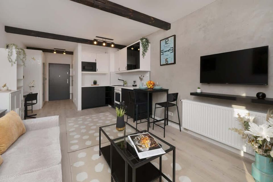 An open-concept living and dining area with exposed wooden ceiling beams, a stylish coffee table, and cozy decor.

