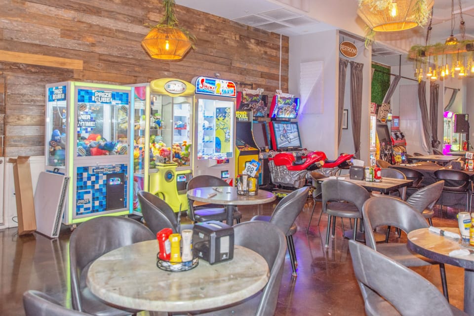 Unwind in this vibrant game room where arcade machines, cozy seating, and warm lighting create your perfect entertainment retreat.