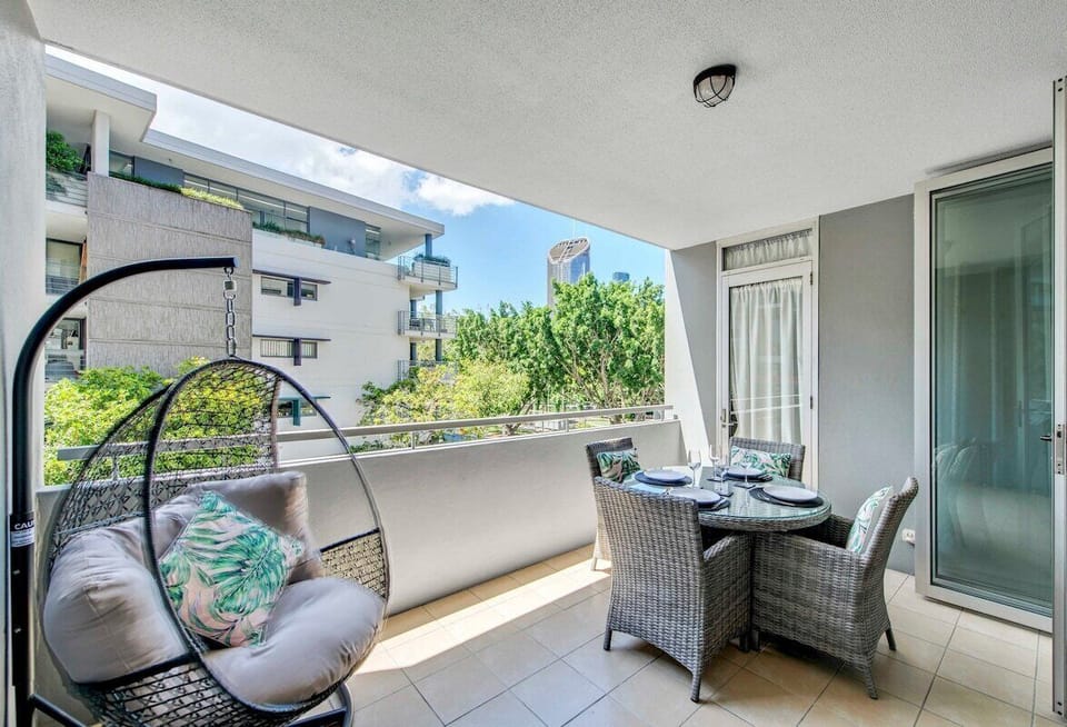 Private balcony with outdoor dining, hanging chair and leafy outlook.