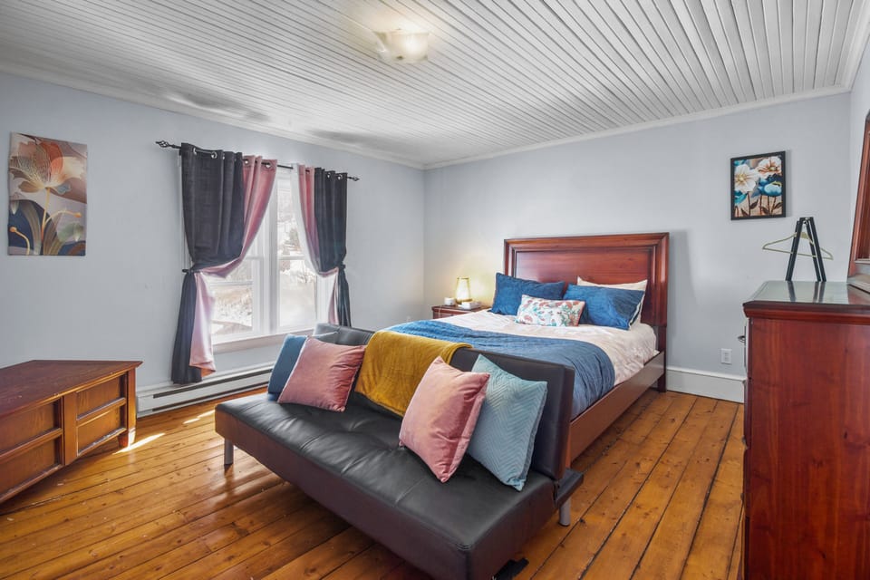 A bedroom with a futon, a wooden bed, and varied throw pillows.