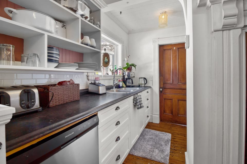 Functional kitchen featuring white cabinetry, open storage, and wooden flooring.