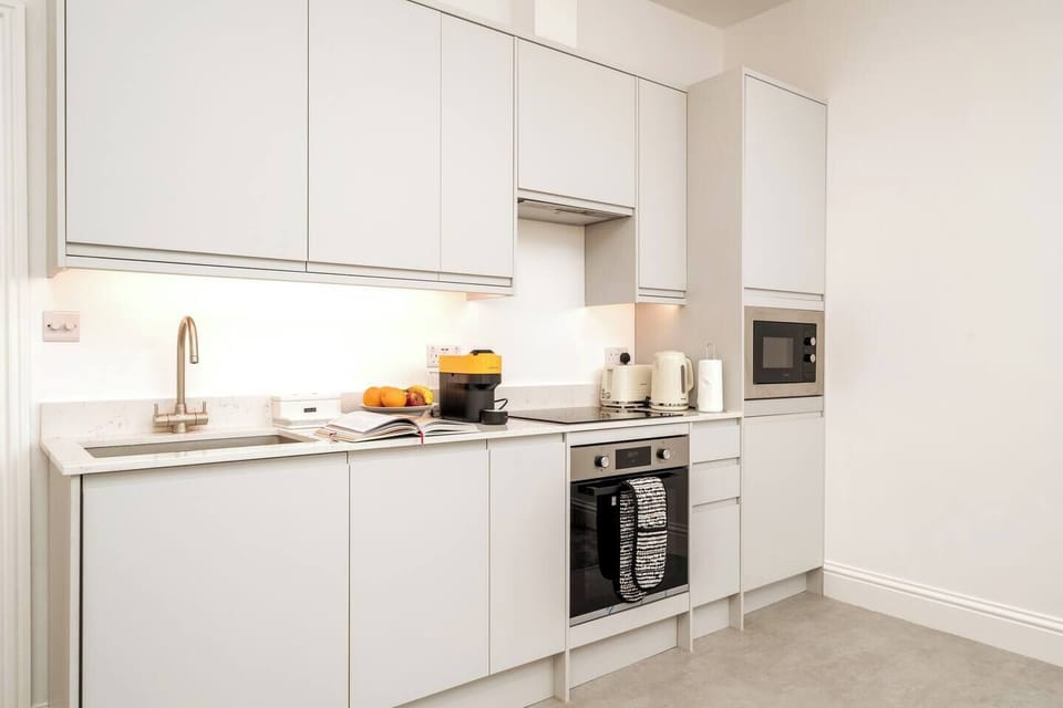 The kitchen features sleek white countertops and cabinets providing a clean and modern aesthetic. The induction cooker offers precise and efficient cooking, allowing you to prepare your favorite dishes with ease. 