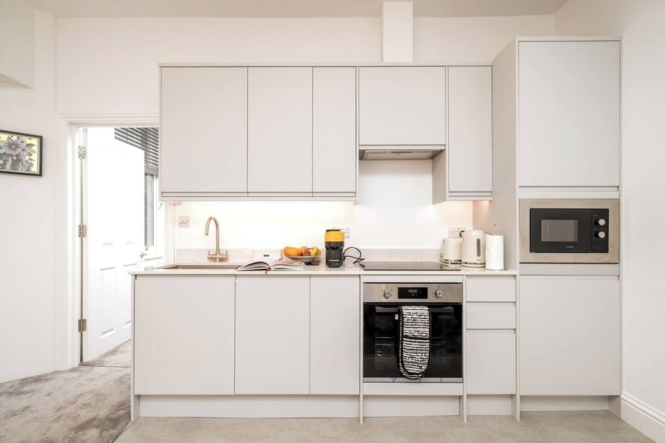 The kitchen features sleek white countertops and cabinets providing a clean and modern aesthetic. The induction cooker offers precise and efficient cooking, allowing you to prepare your favorite dishes with ease. 