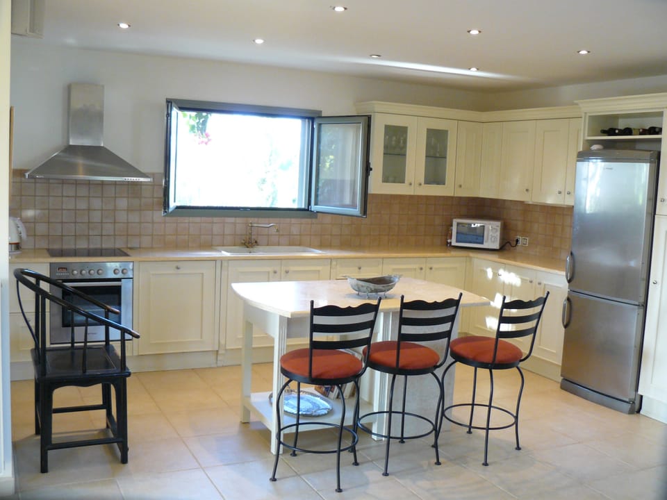 Modern Italian kitchen with marble work surfaces. Looking out to an orange tree
