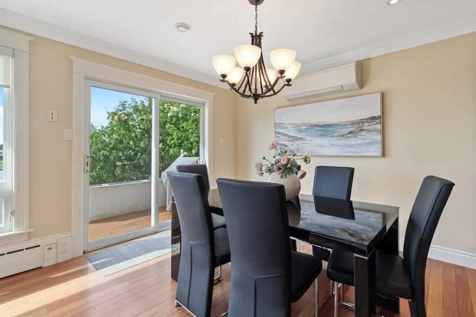 A dining room with a dark wood table, leather chairs, and a view of the river through large windows