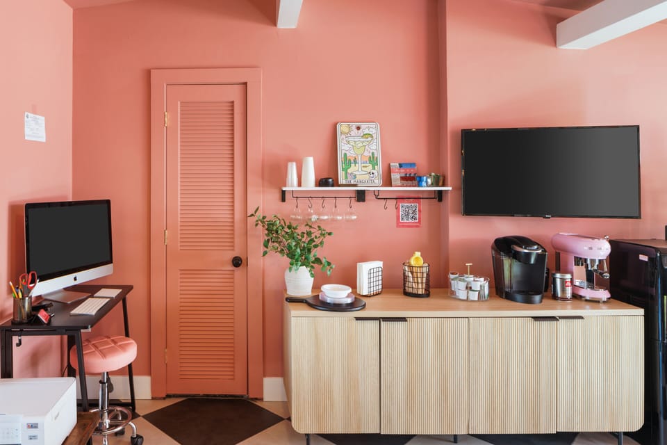 Chic Shared Workspace: Vibrant coral walls, sleek furniture, and coffee delights for your creative escape!
