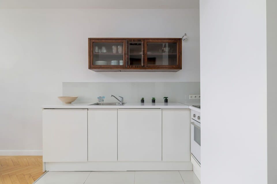 A compact kitchenette with white cabinets, a small stove, and essential appliances for a simple, modern look.


