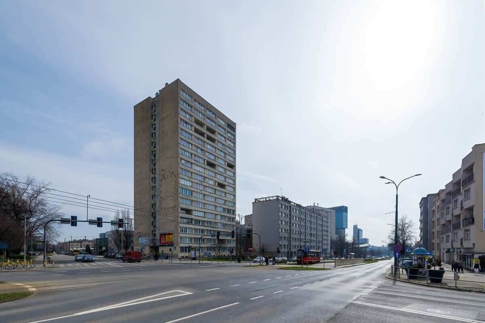 A wide street view of the surrounding neighborhood, featuring a high-rise residential building and open roads.








