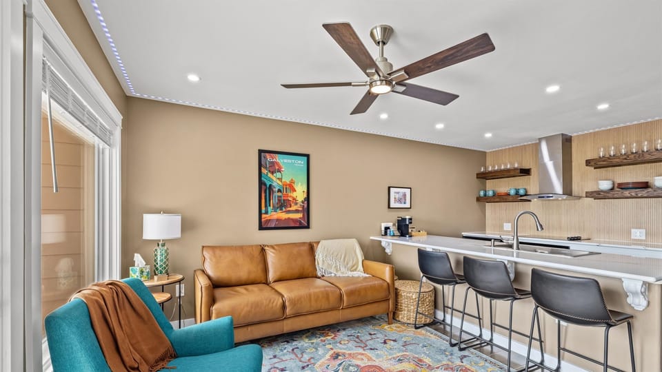Den features a breezy celing fan and comfortable chair and sofa.