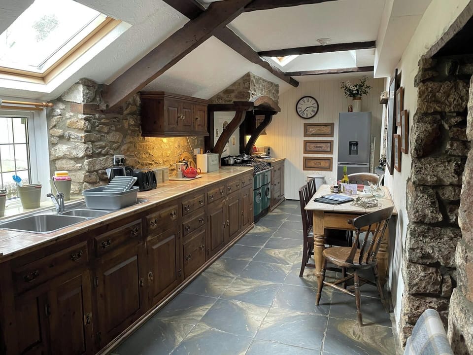 Kitchen with range of kitchen units, washing up sink, stove, dining table and chairs