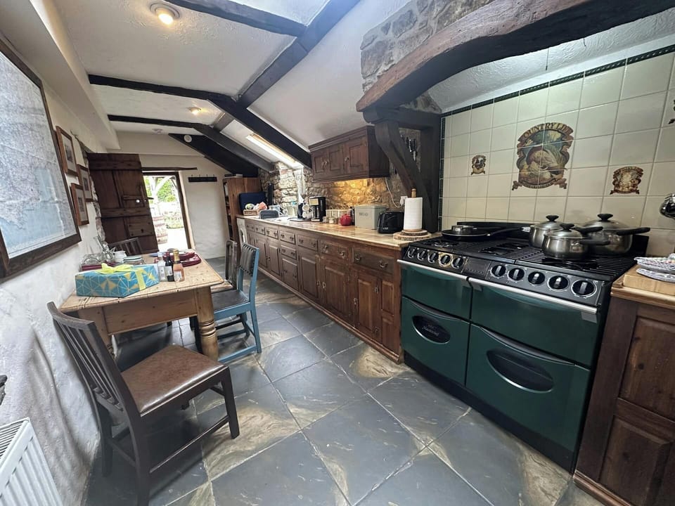 Kitchen with range of kitchen units, washing up sink, stove, dining table and chairs