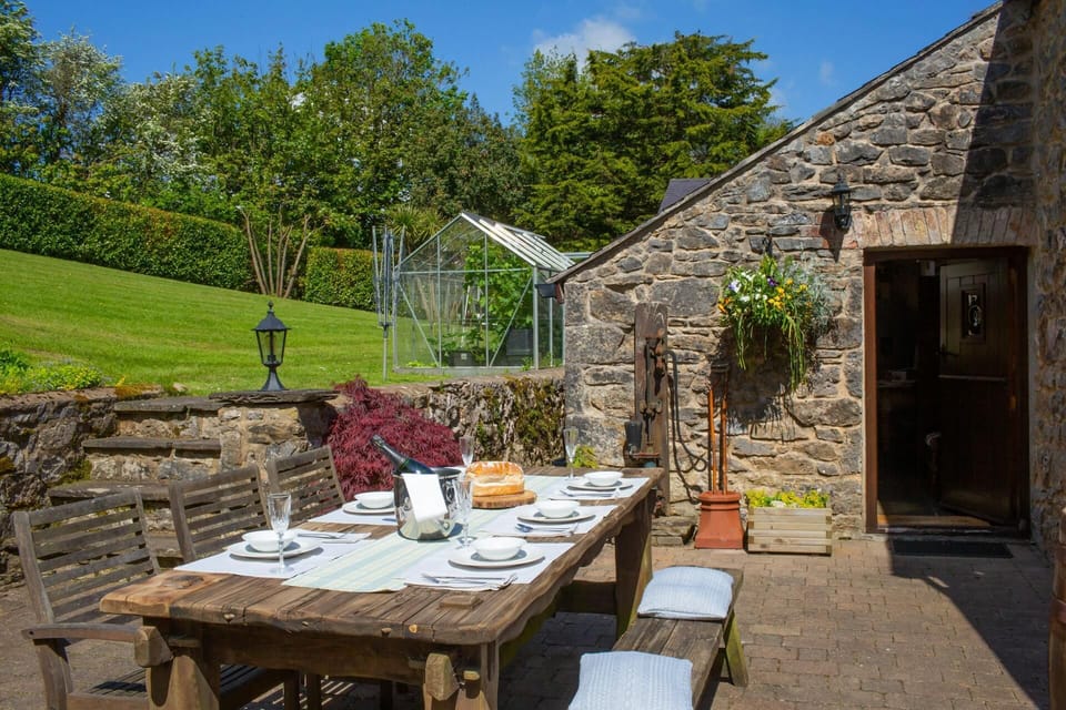 outside wooden garden table to seat 6 set with tablewear and wine, cushions for sitting