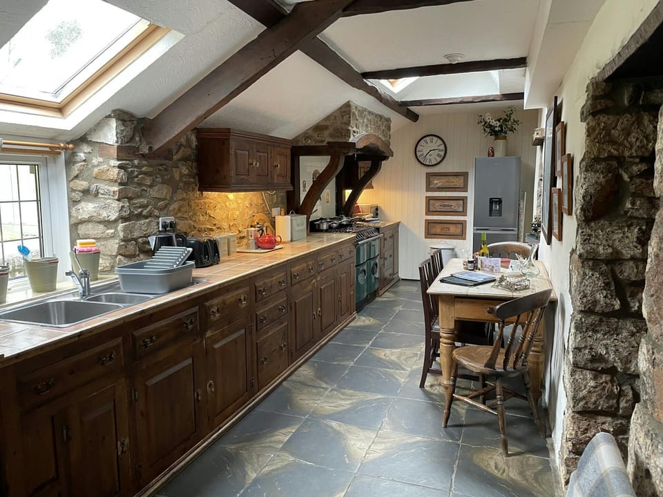 Kitchen with range of kitchen units, washing up sink, stove, dining table and chairs