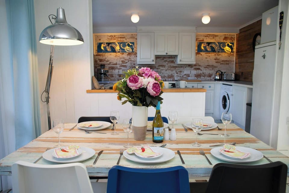 Set dining table with plates and glasses in front of a white kitchen