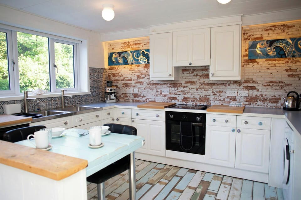 Kitchen interior with large window, white units, and wooden worktops