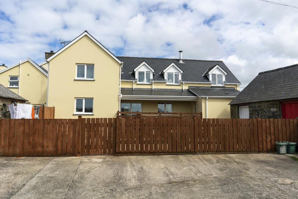 Cnwc Y Boidy. Brown wooden fence with front of cottage behind