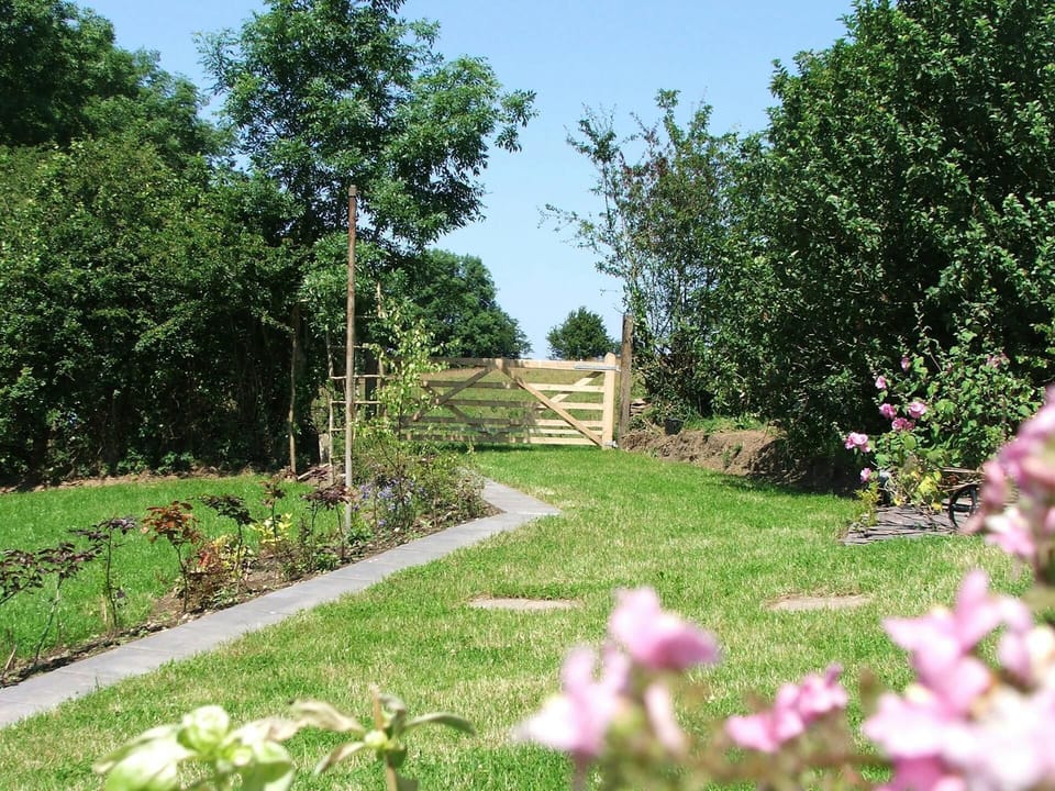 Lawn area with flower beds and gate leading to a meadow