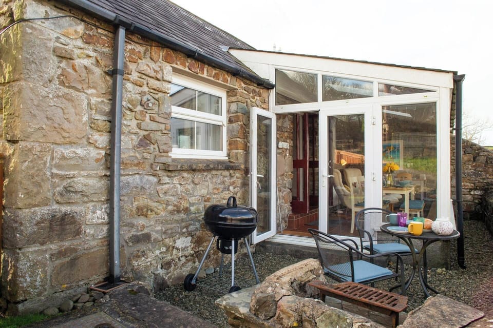 Outside view of Bay Cottage showing conservatory, bbq and outdoor furniture