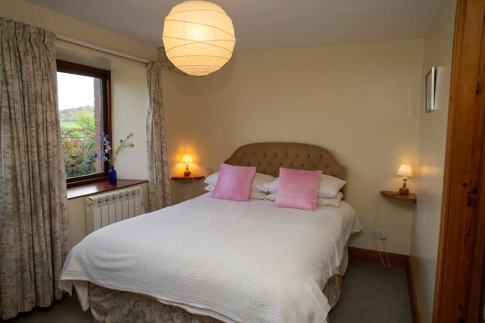 Bedroom with double bed, small shelves with lamps, window