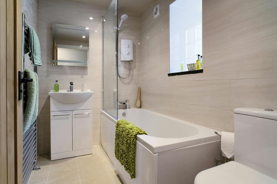 Bathroom with bath and shower over, wash basin and toilet