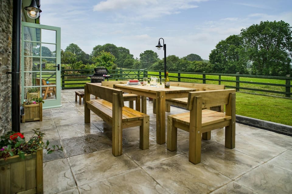 Paved patio with outdoor dining table and chairs, bbq and lawn