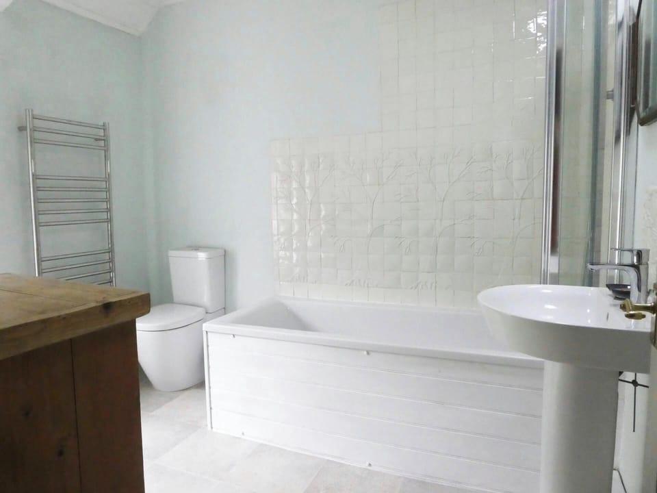 Bathroom with bath with shower over, folding shower screen, washbasin and toilet