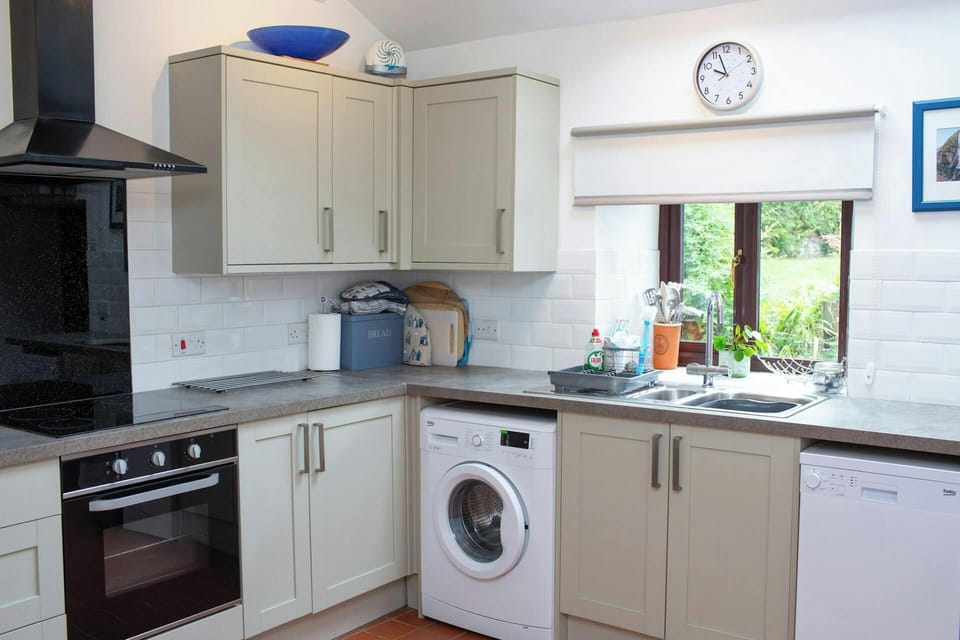 Fitted kitchen with electric oven and extractor fan, washing machine and dishwasher. Window overlooking the garden