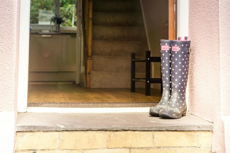 Entrance to the property with a pair of wellies resting at the side of the door.