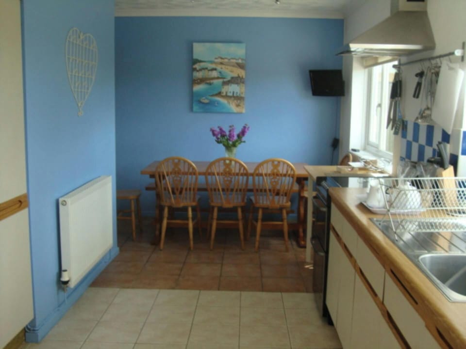 Kitchen-diner with wooden table and chairs against blue wall