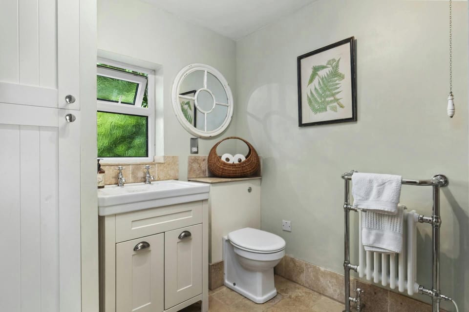 White bathroom vanity with sink and mirror beside a toilet