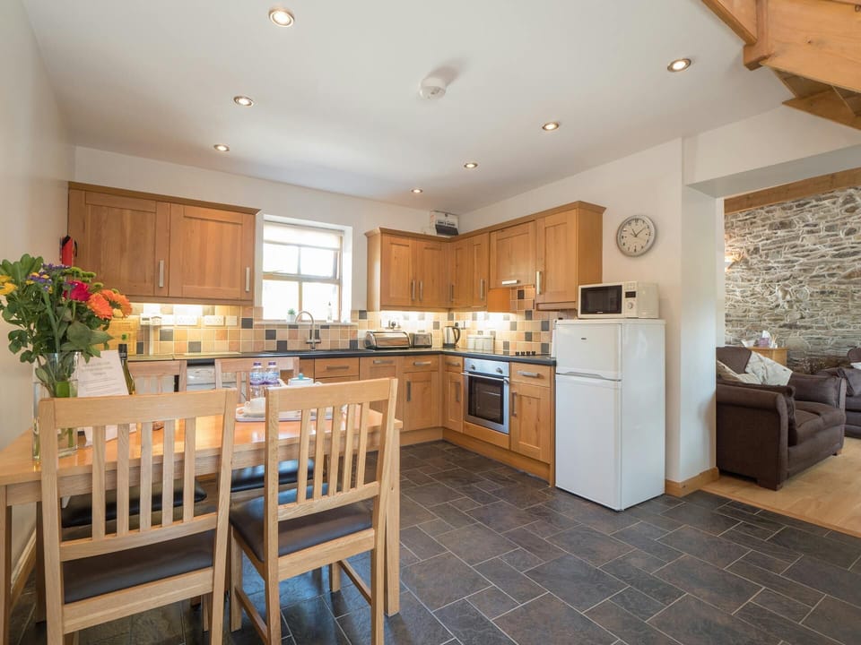 Fitted kitchen with cooker, fridge/freezer, microwave, kettle, toaster; dining table with four chairs