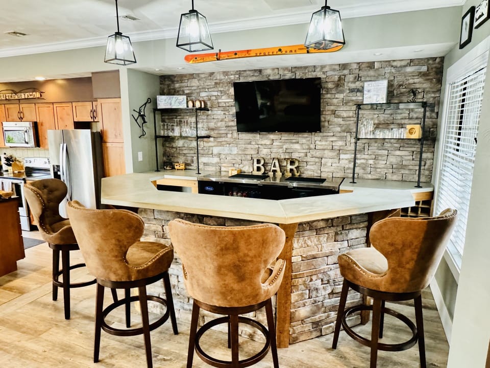 The bar is equipped with glassware and opens to the kitchen/living area