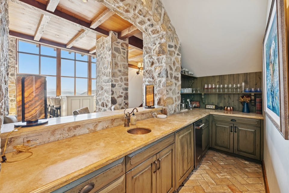Bathroom with dual sinks, stone walls, and large windows overlooking the mountains.