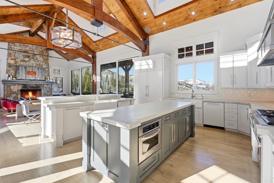 Modern chef's kitchen with white cabinetry and island:
Sleek, sunlit kitchen with white cabinets, stainless steel appliances, and a large central island with pendant lighting.