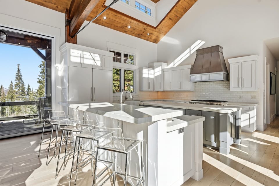 Kitchen island with bar seating and open layout:
Open-concept kitchen showcasing a wide island with barstools, white cabinets, and abundant natural light from large windows.