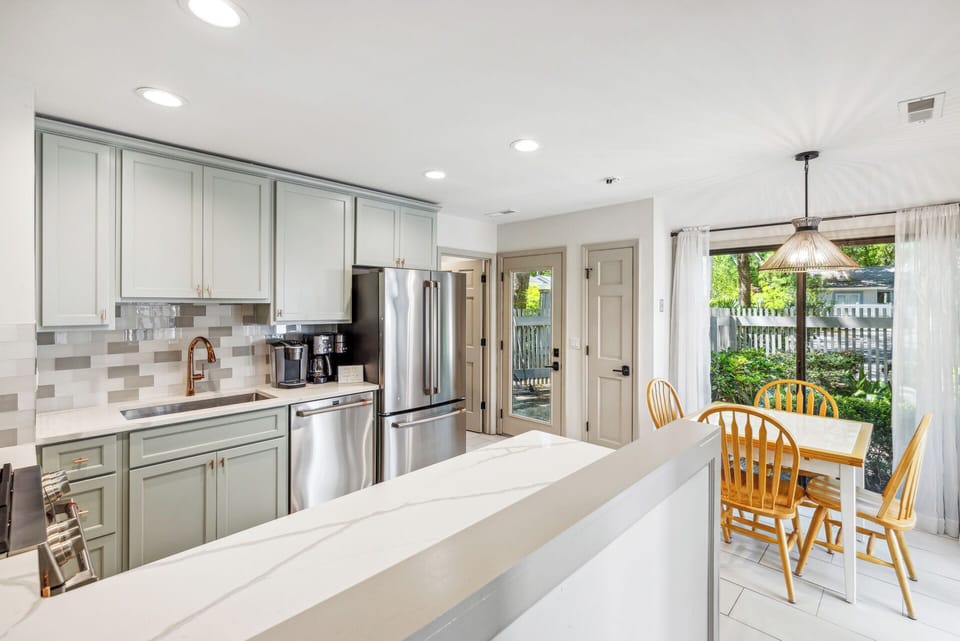 Fully stocked gourmet kitchen with stainless steel appliances, gas stove, Keurig, drip coffee maker and dining area with a courtyard view.