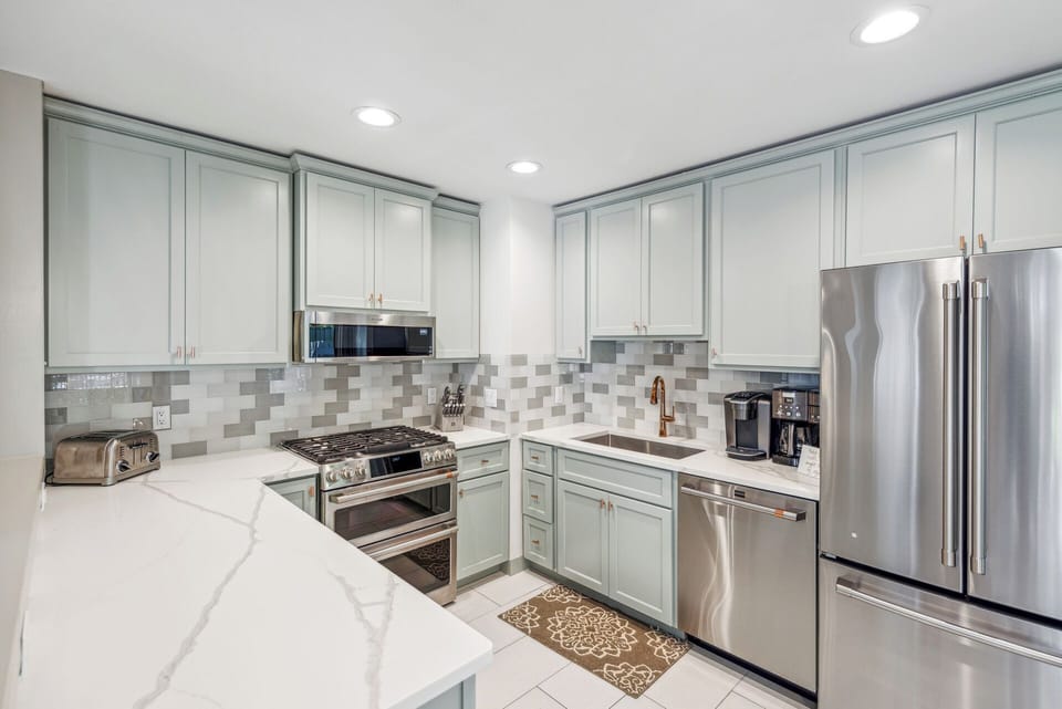Fully stocked gourmet kitchen with stainless steel appliances, gas stove, Keurig, drip coffee maker and dining area with a courtyard view.