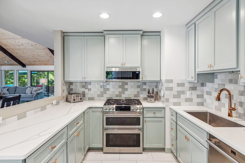Fully stocked gourmet kitchen with stainless steel appliances, gas stove, Keurig, drip coffee maker and dining area with a courtyard view.