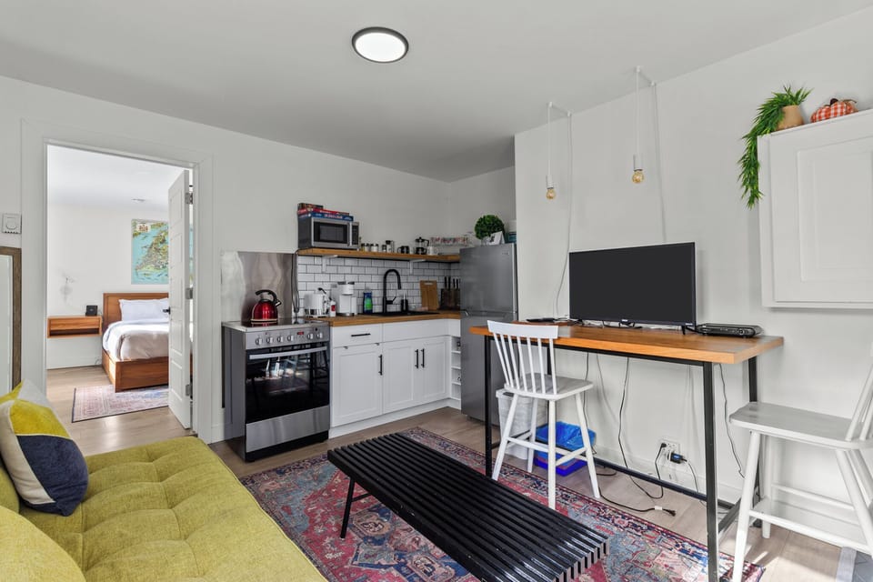 Cozy open-concept living space with a full kitchen, workspace, and a comfy bedroom.