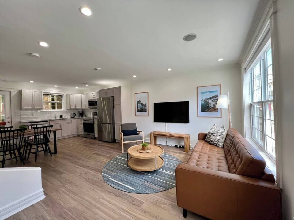 Relax and entertain in this chic open-concept space, featuring a cozy leather sofa, sleek kitchen, and a bright dining area—all bathed in natural light!