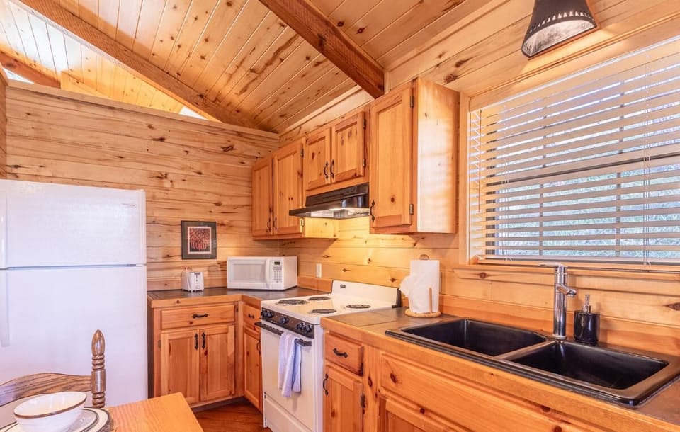 Prepare your favorite meals in Hidden Haven's fully equipped kitchen, featuring warm wooden cabinetry and modern appliances. The dining area offers a cozy spot to enjoy meals with loved ones.