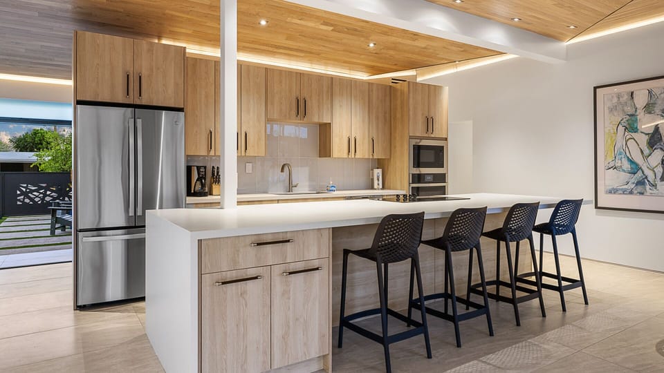 Modern kitchen with light wood cabinets, a white island, and bar seating.