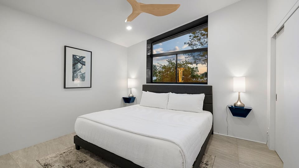 Stylish bedroom with a dark upholstered king bed, shelves, and en suite.