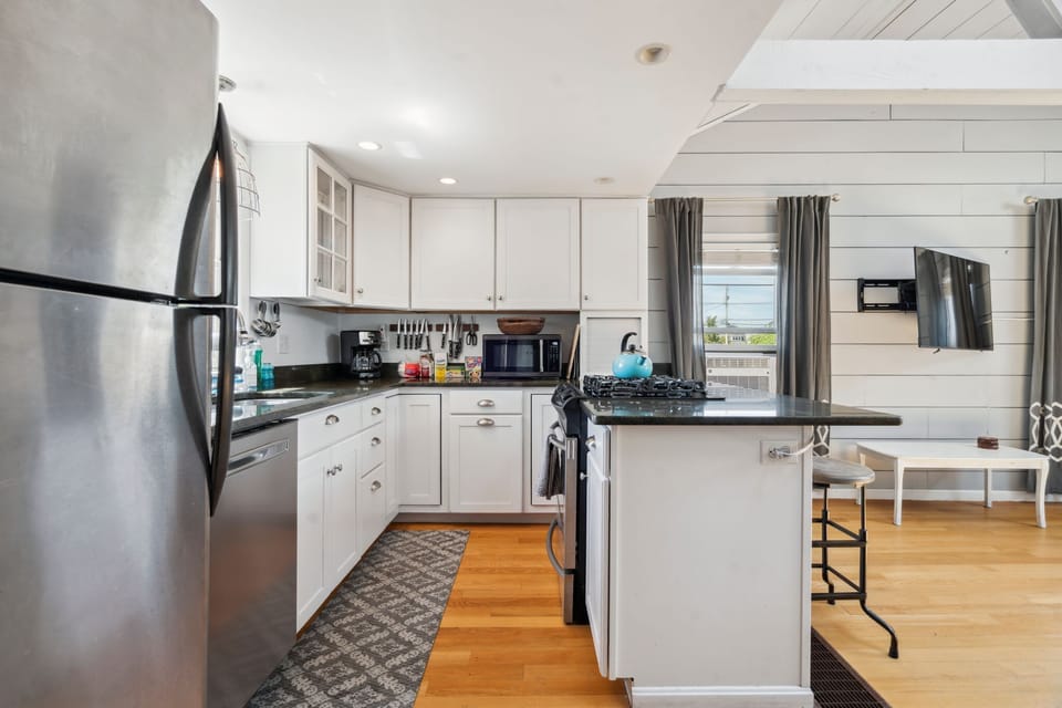 Fully equipped kitchen with all necessary appliances, 3-seater eat-in counter, and 6-person dining table