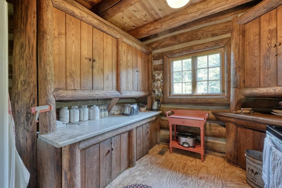 Charming kitchen with rustic cabinets, marble counters & a lovely nature view.