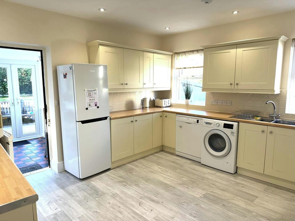 Cream kitchen with wooden worktops, white fridge freezer and washing machine