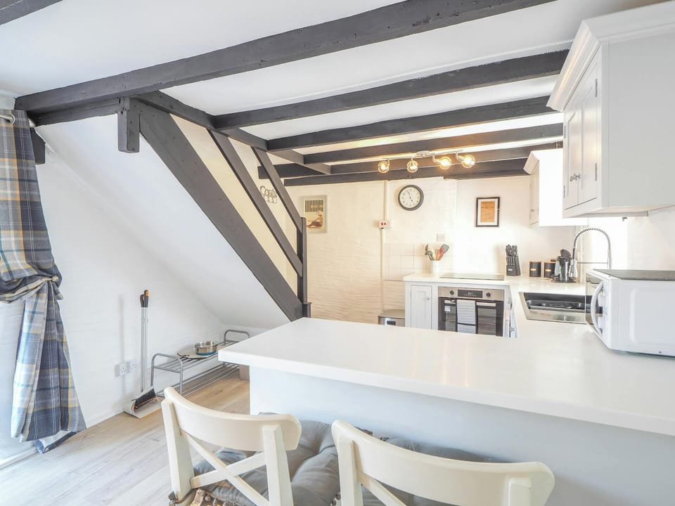 Bright kitchen with breakfast bar, stairs leading to first floor, fitted units