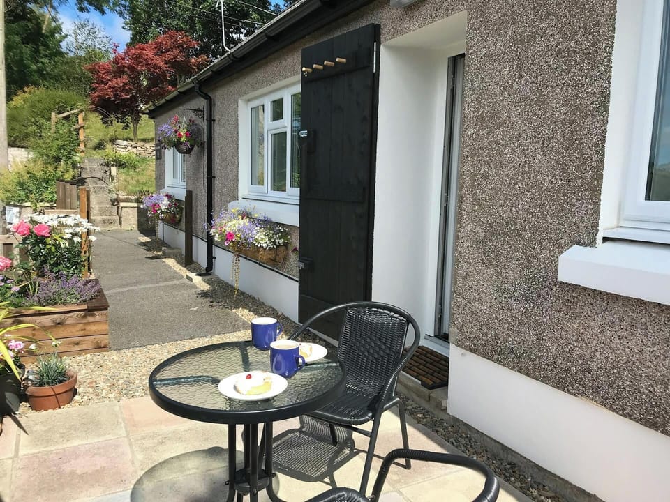 Outdoor patio area with seating and flowers in hanging baskets and window box.