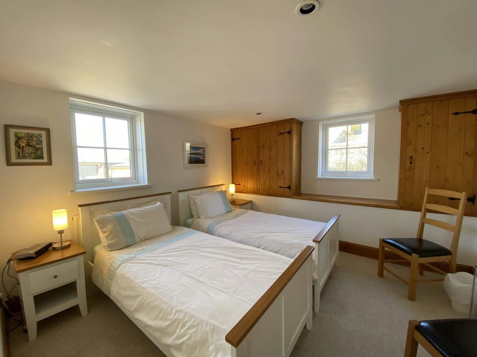 Twin beds, bedside cabinets with lamps, fitted storage cupboards, two chairs and two windows