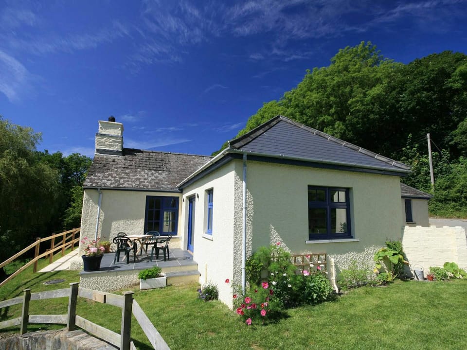Penwaun from the back garden showing patio area with table and chairs, lawn and flowers